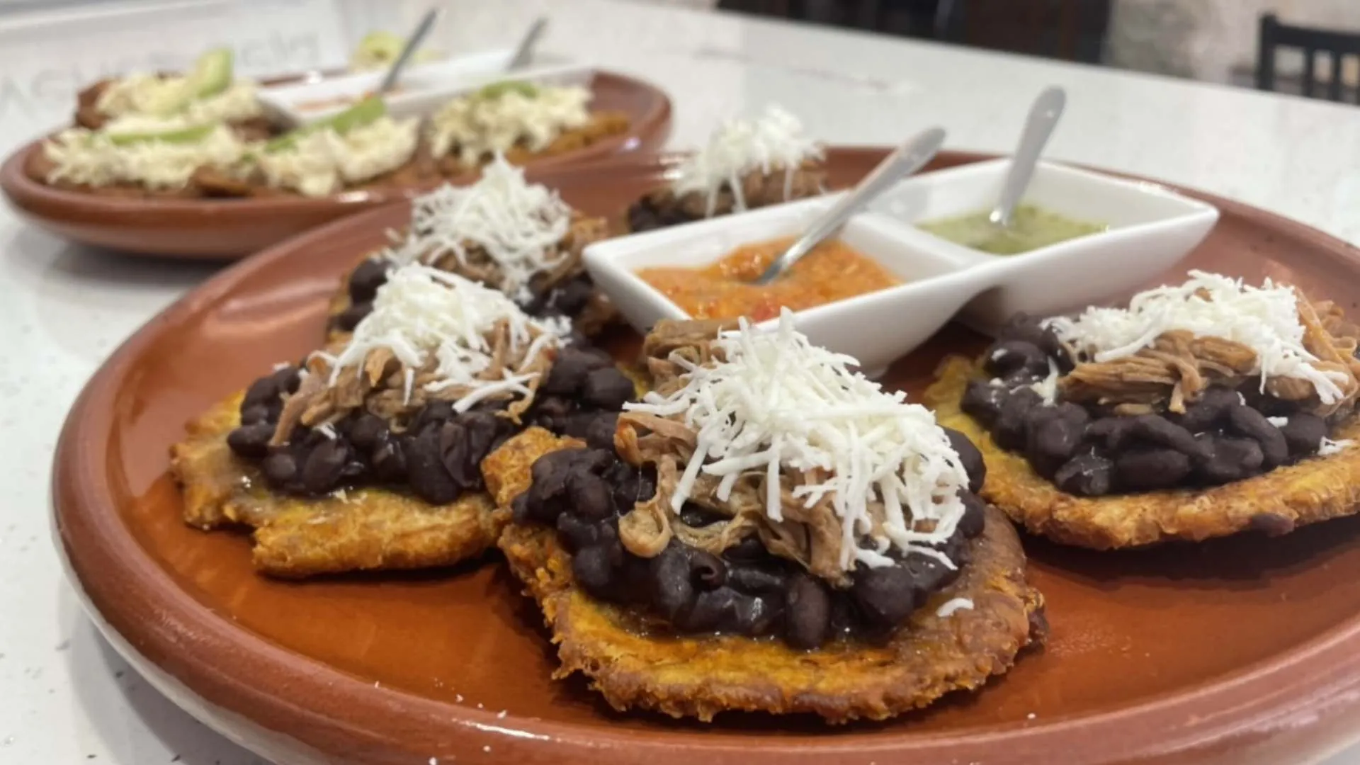 Tostones con caraotas, carne mechada y queso rallado, con salsas