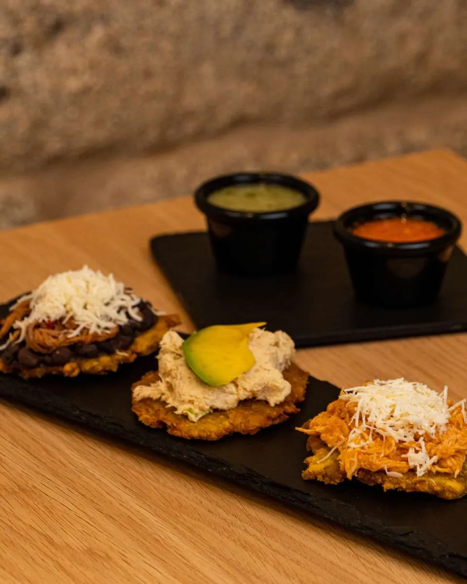 Tres tostones de plátano verde con distintos toppings y salsas